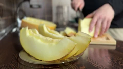 Fresh Melon Slices with Man Cutting Fruit in Background Stock Footage 315991760