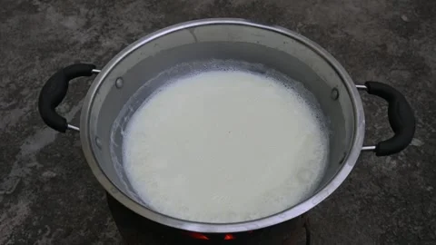 Fresh milk is boiling in a large stainless steel vessel. 库存影片 330824310