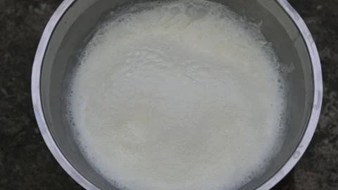 Fresh milk is boiling in a large stainless steel vessel. 库存影片 330824312