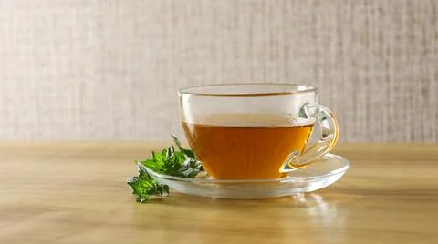 Fresh mint tea in a clear cup on a wooden table with mint leaf nearby in a cozy Stock Photos