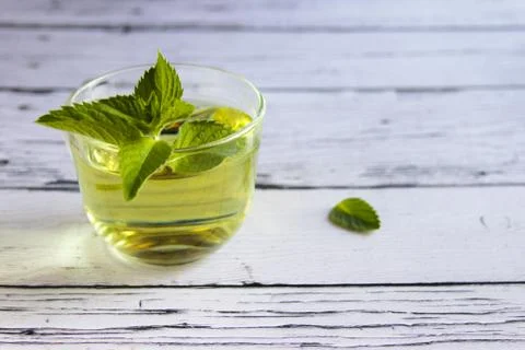 Fresh mint tea concept. Mint tea in transparent cup and one mint leaf. Stock Photos
