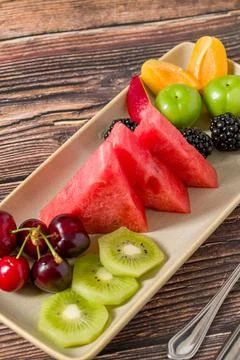 Fresh mixed fruit slices served on rustic wooden table Stock Photos