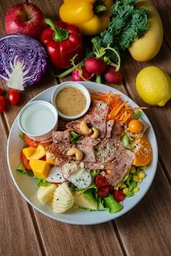 Fresh mixed vegetable and fruit salad bowl with crispy bacon, sesame dressi.. Stock Photos