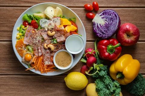 Fresh mixed vegetable and fruit salad bowl with crispy bacon, sesame dressi.. Stock Photos