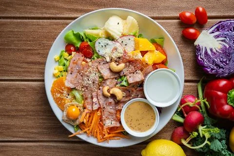 Fresh mixed vegetable and fruit salad bowl with crispy bacon, sesame dressi.. Stock Photos