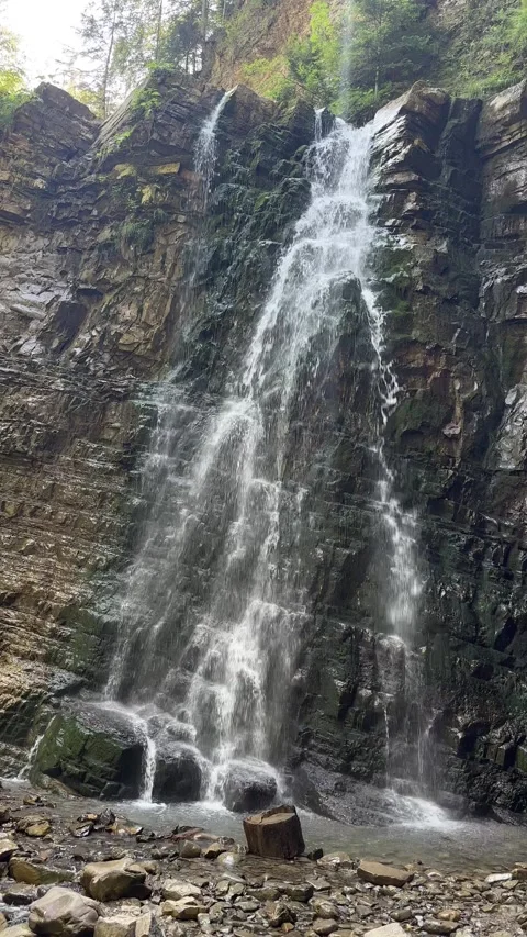 Fresh mountain water stream rushing down a layered stone wall Video stock 336260323