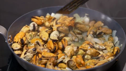Fresh mussels heating inside dry pan, gentle steam rising above tender seafood Stock Footage 321817895