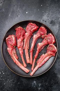 Fresh mutton chops, raw lamb meat cutlets on a plate. black background. top.. Stock Photos