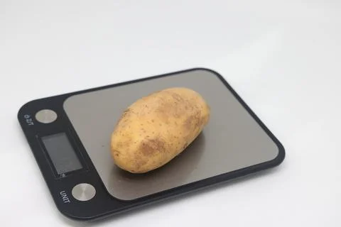 Fresh natural potatoes on electronic kitchen scales. Raw materials for making Stock Photos