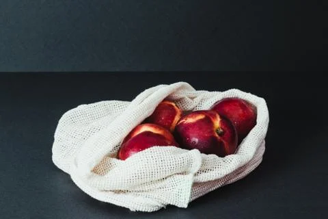 Fresh nectarines in string bag, shopper on the black background, zero waste c Stock Photos