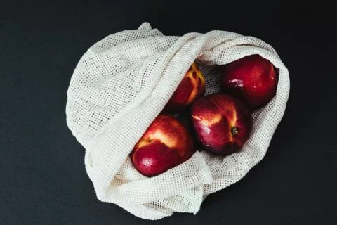 Fresh nectarines in string bag, shopper on the black background Stock Photos