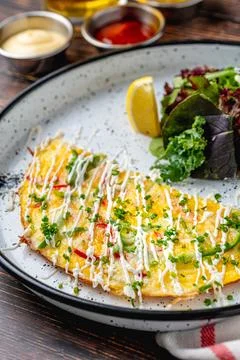 Fresh omelette served with salad on rustic table Stock Photos