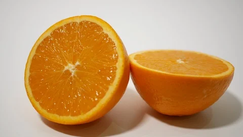 Fresh orange cut in half on white close up pan right Stock Footage 99259573