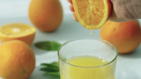 A fresh orange is gently squeezed, releasing its juice. Stock Footage 243739686
