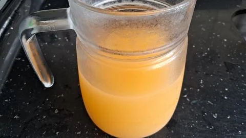 Fresh orange juice inside a clear glass pitcher on table Stock Photos