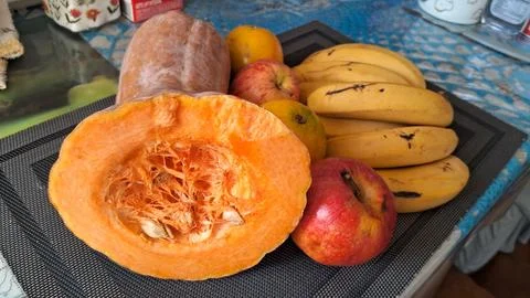 Fresh orange pumpkin cut in half with assorted healthy fruits Stock Photos