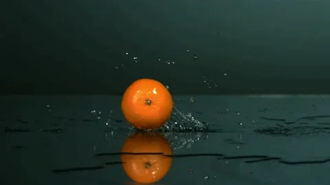 Fresh orange rolls on wet surface with water splash Stock Footage 327514497