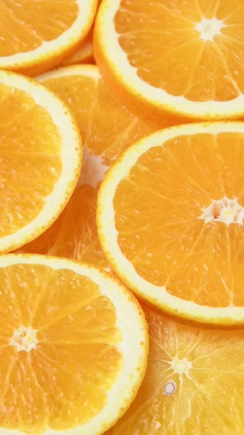 Fresh orange slices rotate in a vertical frame, revealing juicy citrus flesh and Stock Footage 346673077
