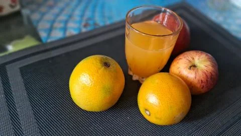 Fresh oranges and red apples with a glass of juice Stock Photos