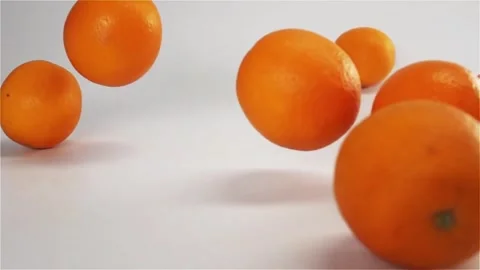 Fresh oranges bounce and roll dynamically across a clean white surface in s.. Stock Footage 297451533