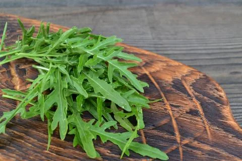 Fresh organic arugula on rustic cutting board, diagonal photo with copy space Stock Photos