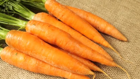 Fresh organic bunch of carrots rotating on a burlap background Stock Footage 342437365