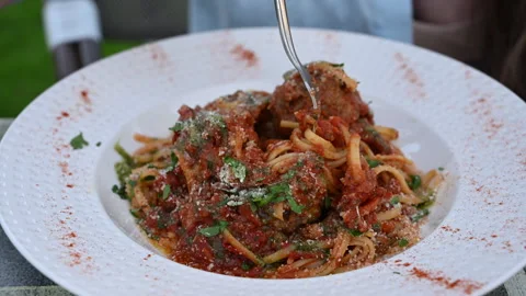 Fresh parmesan being tossed over a plate of spaghetti with tomato sauce and Stock Footage 336983044