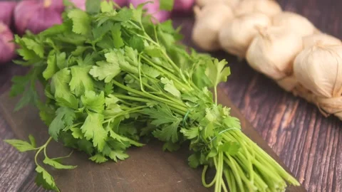 Fresh Parsley Bunch With Garlic Braid on Rustic Wooden Kitchen Surface for Stock Footage 338220019