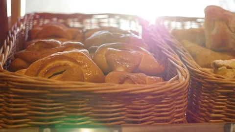 Fresh pastries in a basket on showcase, in the store. Sun rays through pastries Video stock 80916663