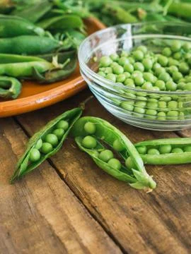 Fresh peas and its shells on a wooden table Foto stock