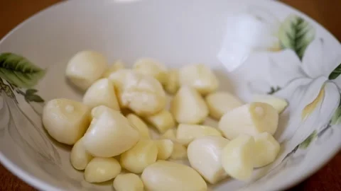 Fresh Peeled Garlic Cloves Falling Into Floral Bowl In Slow Motion Stock Footage 330116799