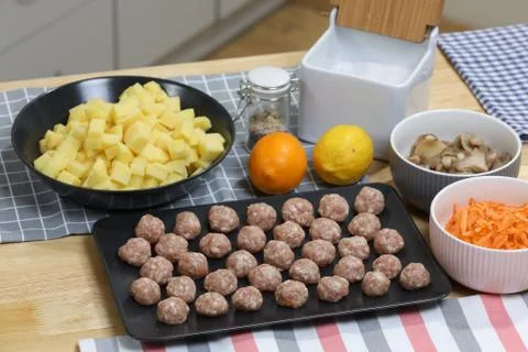 Fresh peeled potato, carrot, lemon and meat balls on a kitchen table. Stock Photos
