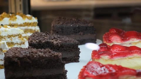 Fresh pieces of cake and pie lie on the showcase of a pastry shop, close up Stock Footage 243218448