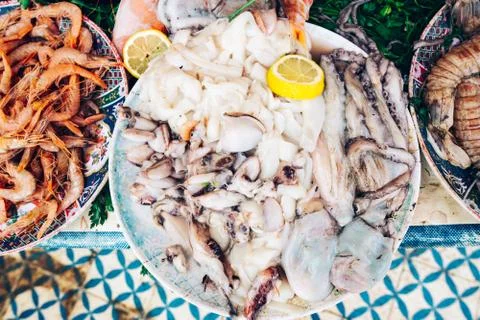 Fresh pieces of squid and octopus on a plate. Seafood market counter. Stock Photos