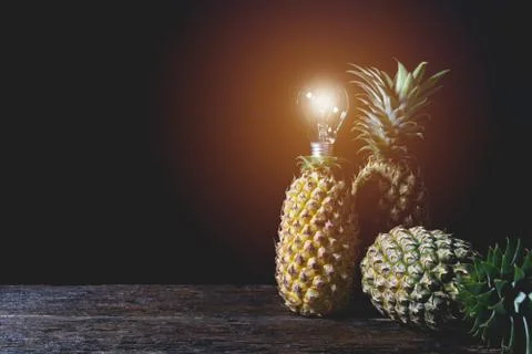 Fresh pine apple with light bulb, vitamin and good for health on wooden table Stock Photos