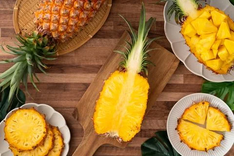 Fresh pineapple chunks served in a pineapple bowl on wooden table background. Stock Photos