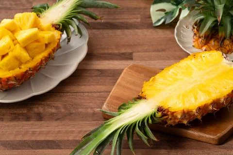 Fresh pineapple chunks served in a pineapple bowl on wooden table background. Stock Photos