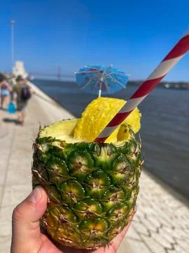 Fresh pineapple drink served inside a hollowed fruit with striped straw Stock Photos