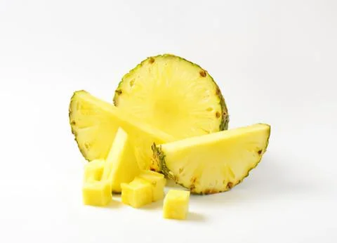 Fresh pineapple slices and chunks on table Stock Photos