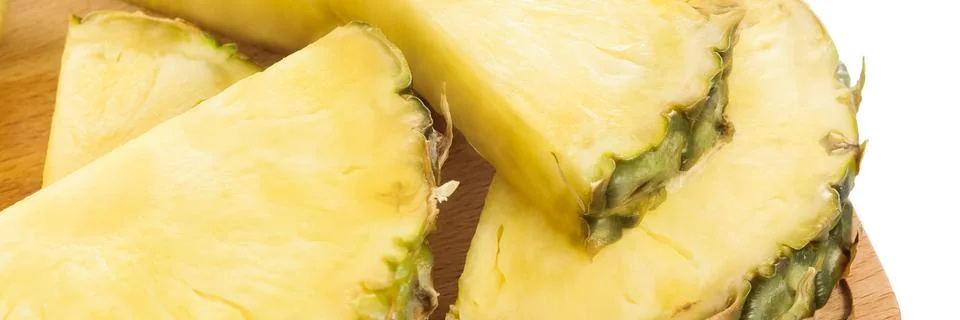 Fresh pineapple slices on brown chopping board. Stock Photos