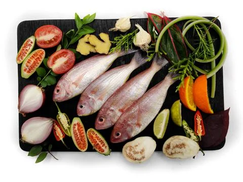 Fresh Pink Perch (thread finned Bream) Decorated with vegetables on a wooden  Stock Photos