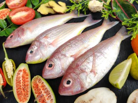 Fresh Pink Perch (thread finned Bream) Decorated with vegetables on a wooden  Stock Photos