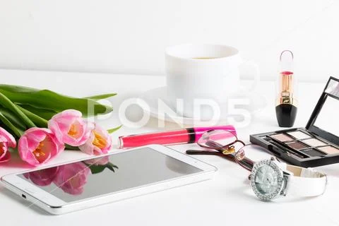 Fresh pink tulips, white tablet, cosmetics, wristwatch, cup of coffee, glasse Stock Photos