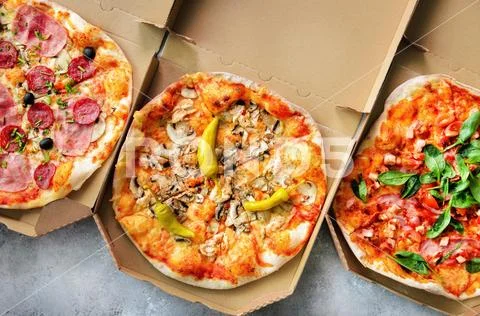 Fresh pizza in delivery box on grey concrete background. Top view, copy space Stock Photos