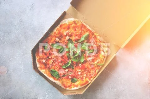 Fresh pizza in delivery box on grey concrete background. Top view, copy space Stock Photos