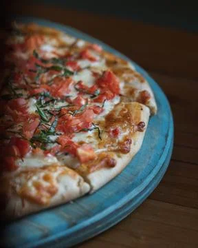 Fresh pizza rests on a rustic blue tray Stockfoto's