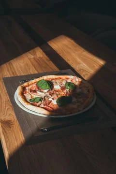 Fresh pizza on table under sunlight on restaurant Stock Photos