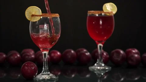 Fresh plum drink decorated with a slice of lemon and an ice cube pouring in a... Video stock 157345916