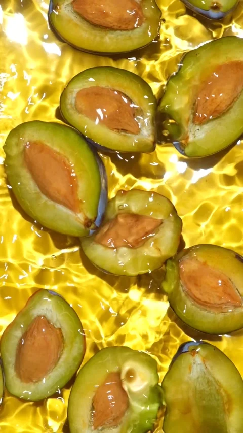 Fresh plum halves with pits floating in clean water overhead view. Stock Footage 346683644