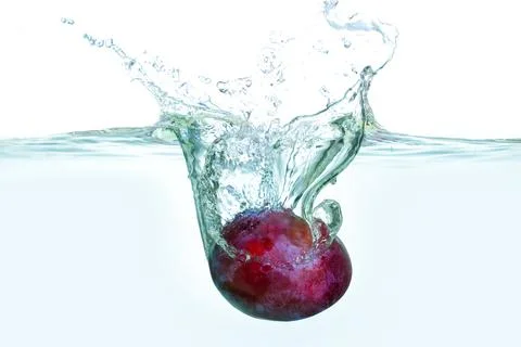 Fresh Plum Making Splash in Clear Water Surface with Bubbles Foto stock